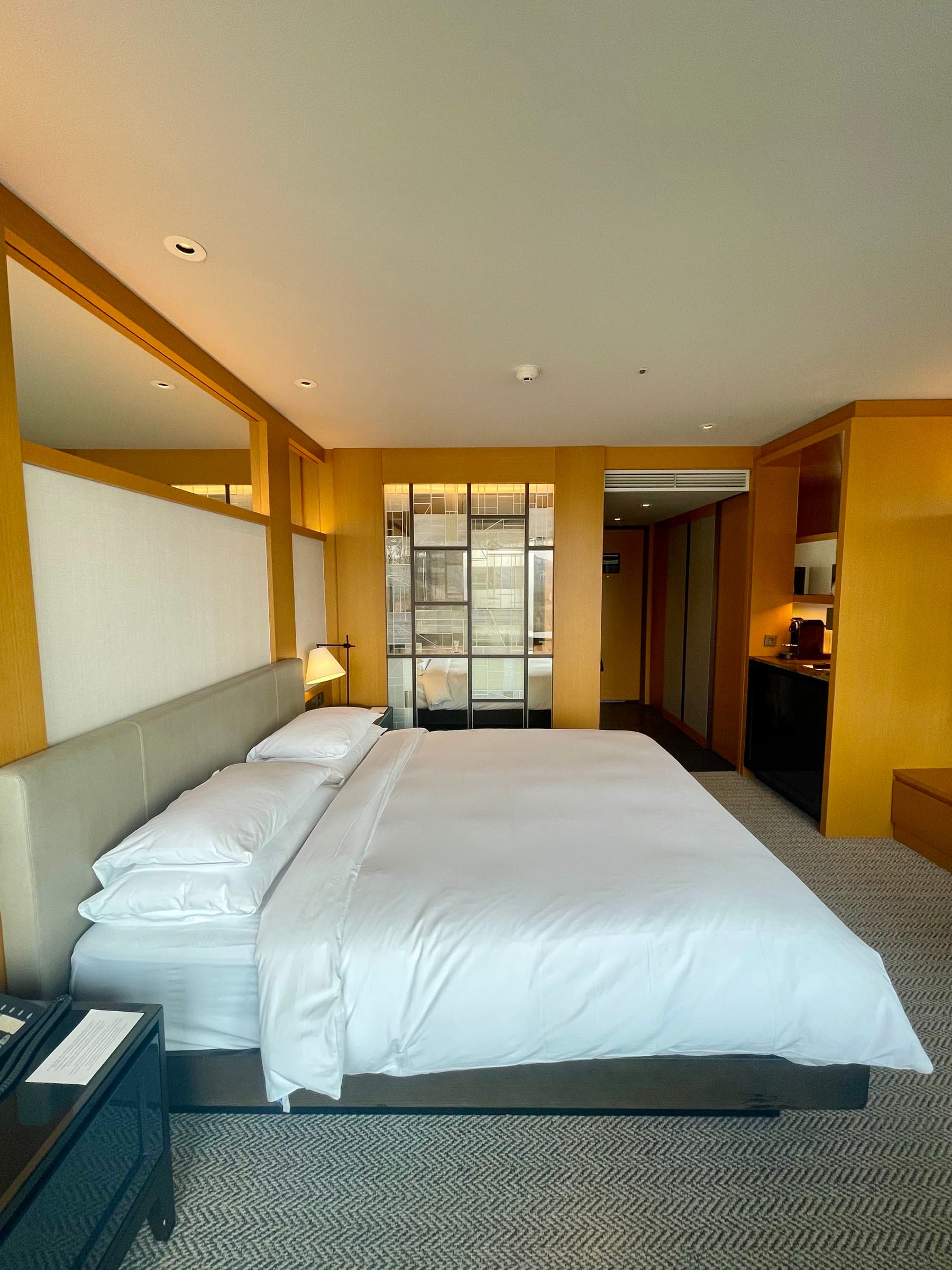 Giường King giữa nội thất gỗ và ánh đèn vàng ấm